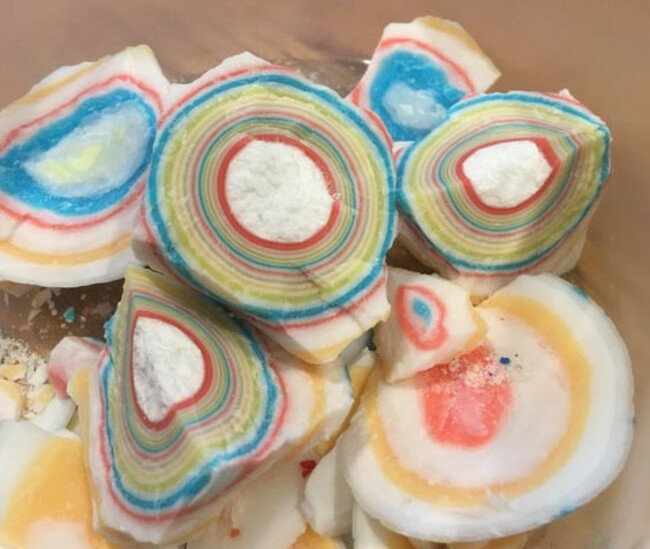 A bowl of jawbreaker candies, each cracked open, revealing concentric colored rings.